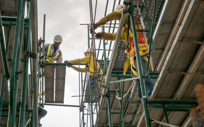 Builders climbing on scaffolding at construction site